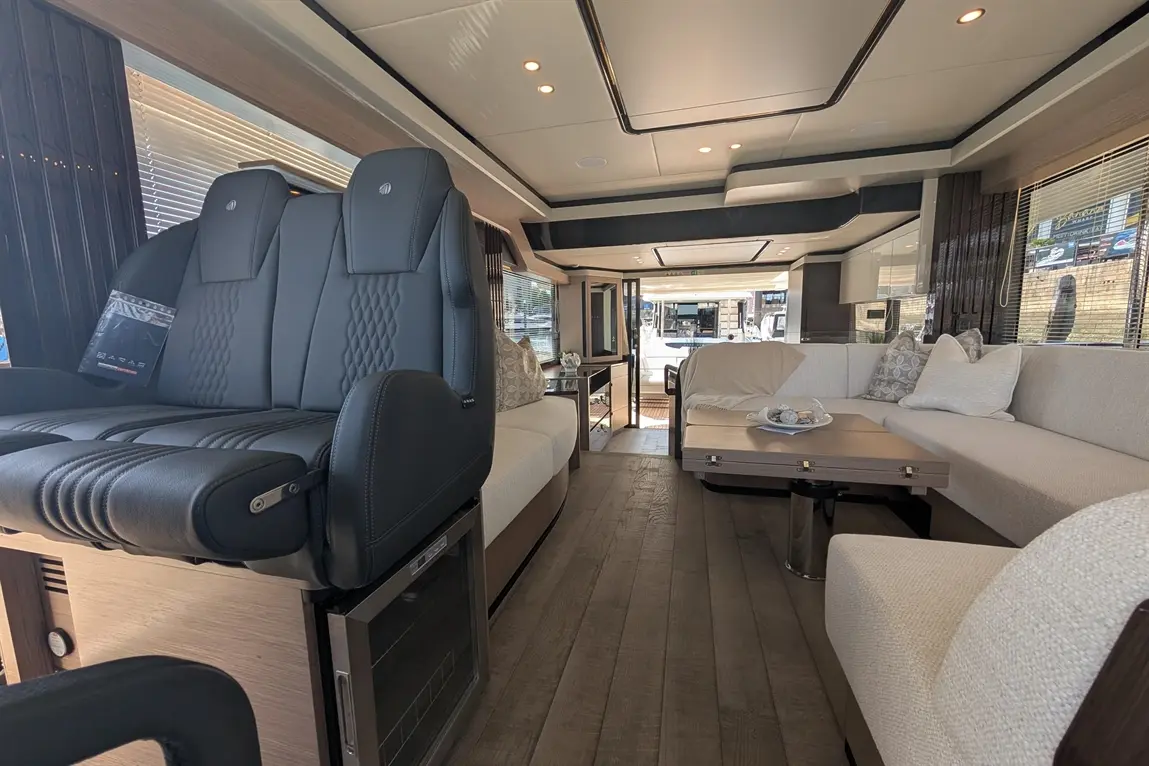 Modern interior of a luxury motorhome featuring leather seats, plush sofa, dining table, and ambient lighting.